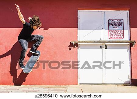 Stock Image - Man skating near red wall. Fotosearch
