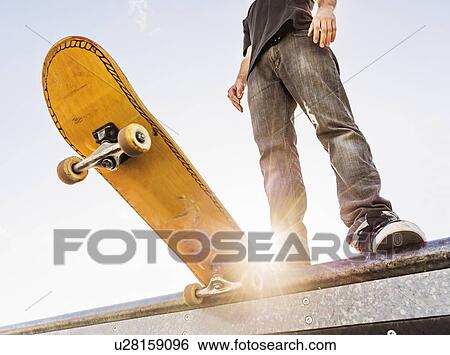 Man with skateboard at the edge of ramp View Large Photo Image Stock Photograph - Man with skateboard at the edge of ramp. Fotosearch