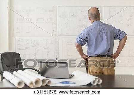 Mature architect looking at blueprints in office View Large Photo Image Stock Photo - Mature architect looking at blueprints in office. Fotosearch