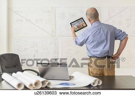 Mature architect using digital tablet in office View Large Photo Image Stock Image - Mature architect using digital tablet in office. Fotosearch