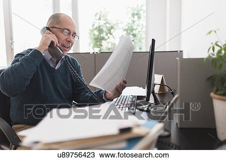 Mature businessman using landline phone in office View Large Photo Image Stock Image - Mature businessman using landline phone in office. Fotosearch