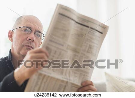 Mature man reading newspaper on sofa View Large Photo Image Stock Image - Mature man reading newspaper on sofa . Fotosearch