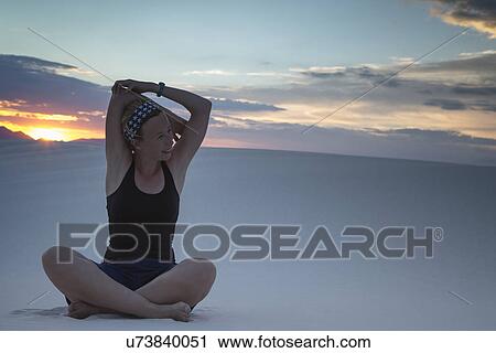Stock Image - Mid-adult woman doing yoga in desert. Fotosearch