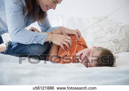 Mother and son (6-7) playing in bed View Large Photo Image Stock Photograph - Mother and son (6-7) playing in bed. Fotosearch