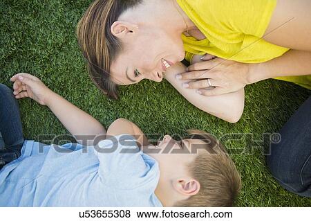 Stock Photo - Mother and son (6-7) relaxing on grass. Fotosearch