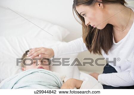 Stock Image - Mother caring for ill son (6-7) . Fotosearch