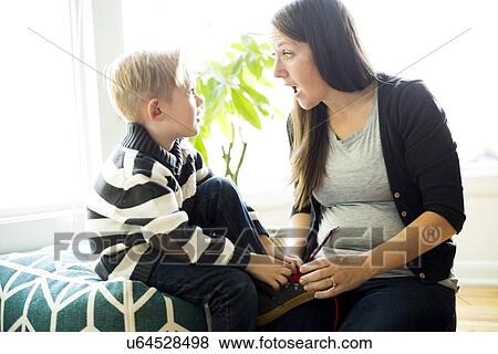 Stock Photo - Mother helping son (6-7) putting shoe on. Fotosearch