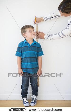 Mother measuring son (6-7) with ruler View Large Photo Image Picture - Mother measuring son (6-7) with ruler. Fotosearch