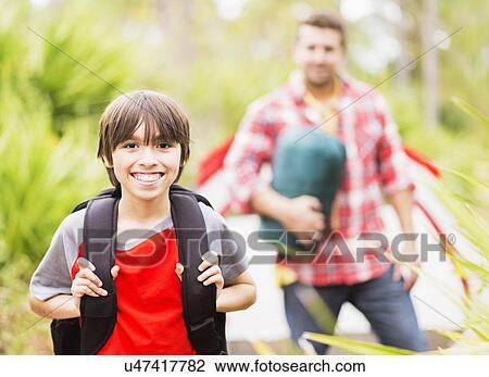 Stock Image - Portrait of boy (12-13) in forest with his father in background. Fotosearch