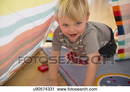 Stock Image - Portrait of boy (2-3) crawling in tent. Fotosearch