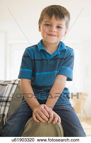 Portrait of boy (6-7) sitting on sofa View Large Photo Image Stock Image - Portrait of boy (6-7) sitting on sofa. Fotosearch