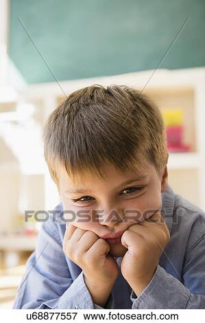 Stock Photo - Portrait of frustrated boy (6-7) sitting in classroom. Fotosearch