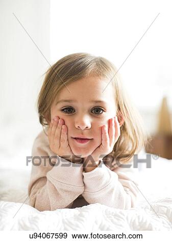 Portrait of girl (4-5) lying on bed View Large Photo Image Stock Photo - Portrait of girl (4-5) lying on bed. Fotosearch