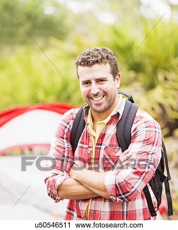 Stock Image - Portrait of man in front of tent with backpack. Fotosearch