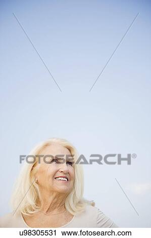 Portrait of senior woman against blue sky View Large Photo Image Stock Image - Portrait of senior woman against blue sky. Fotosearch