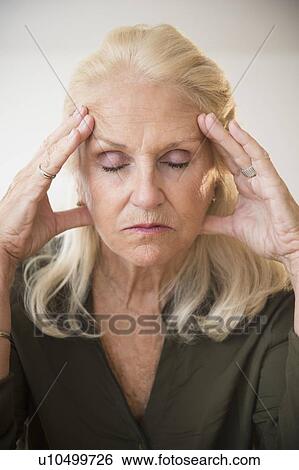 Stock Photograph - "Portrait of senior woman holding head, eyes closed". Fotosearch