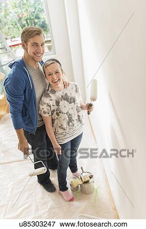 Portrait of smiling couple painting wall View Large Photo Image Stock Photo - Portrait of smiling couple painting wall. Fotosearch