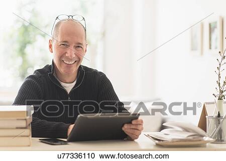 Stock Image - Portrait of smiling mature man working in home office . Fotosearch
