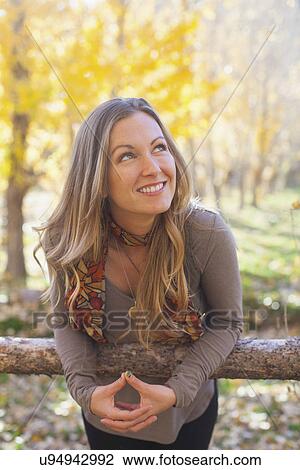 Stock Image - Portrait of smiling woman in forest. Fotosearch