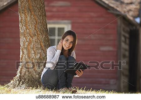 Stock Photo - Portrait of woman sitting outdoors with tablet . Fotosearch