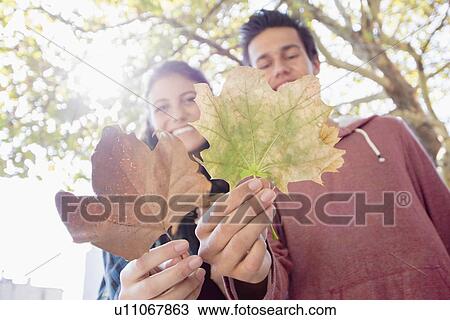 Stock Image - Portrait of young couple showing leaves. Fotosearch