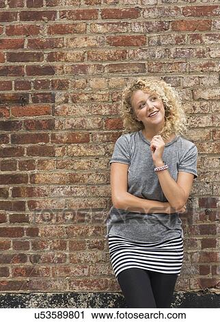 Portrait of young woman in front of brick wall View Large Photo Image Stock Image - Portrait of young woman in front of brick wall. Fotosearch