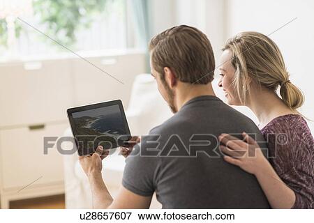 Rear view of couple looking at picture on digital tablet View Large Photo Image Stock Photo - Rear view of couple looking at picture on digital tablet. Fotosearch