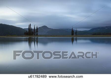 Scenic view of lake and hills at dawn View Large Photo Image Stock Photo - Scenic view of lake and hills at dawn. Fotosearch
