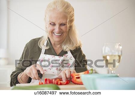 Stock Photo - Senior woman cutting pepper. Fotosearch