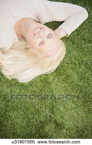 Senior woman lying on grass View Large Photo Image Stock Image - Senior woman lying on grass. Fotosearch