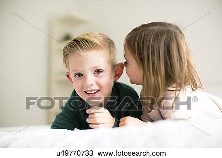 Stock Image - "Siblings (2-3, 4-5) whispering in bedroom". Fotosearch
