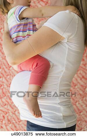 Stock Photography - Side-view of pregnant woman with daughter (2-3). Fotosearch