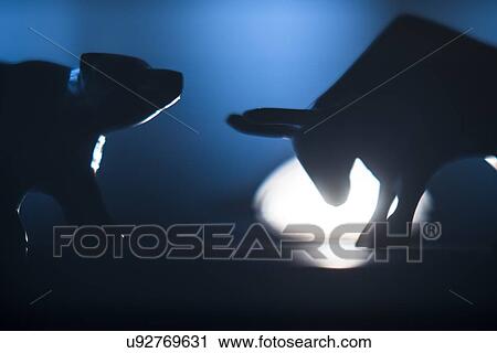 Stock Image - Silhouettes of figurines of bull and bear in spot light. Fotosearch