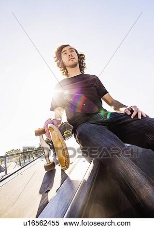 Skateboarder resting in skatepark View Large Photo Image Stock Photography - Skateboarder resting in skatepark. Fotosearch