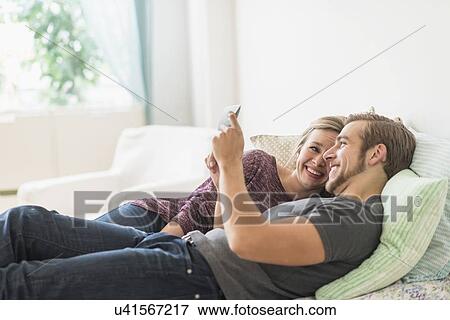 Smiling couple lying on bed and using digital tablet View Large Photo Image Stock Photo - Smiling couple lying on bed and using digital tablet. Fotosearch