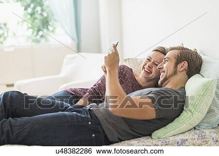 Smiling couple lying on bed and using digital tablet View Large Photo Image Stock Photograph - Smiling couple lying on bed and using digital tablet. Fotosearch