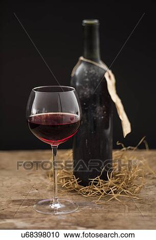 "Still life with red wine glass and bottle on wooden table, studio shot" View Large Photo Image Stock Image - "Still life with red wine glass and bottle on wooden table, studio shot". Fotosearch