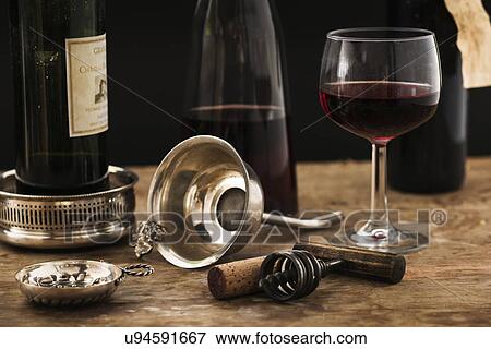 Stock Photo - "Still life with red wine glass, carafe and bottle on wooden table, studio shot". Fotosearch