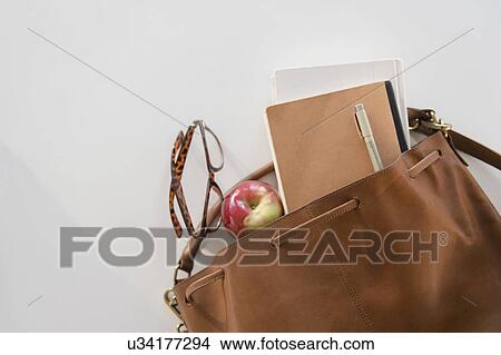 Studio Shot of shoulder bag with apple and notebook in it View Large Photo Image Picture - Studio Shot of shoulder bag with apple and notebook in it. Fotosearch