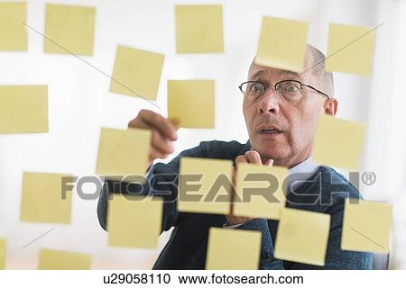 Surprised businessman arranging adhesive notes on glass wall View Large Photo Image Stock Image - Surprised businessman arranging adhesive notes on glass wall. Fotosearch