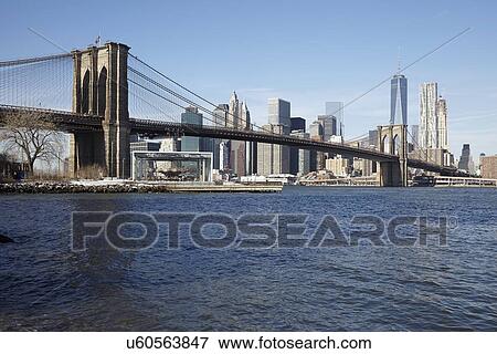Stock Photo - View of waterfront cityscape with suspension bridge. Fotosearch