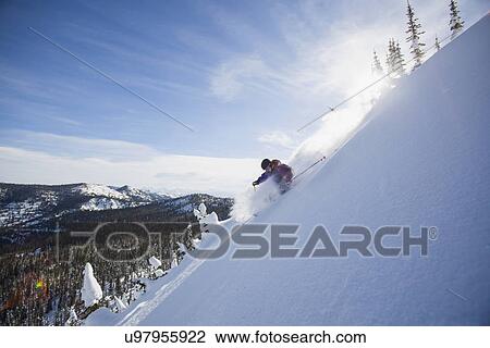 Stock Image - View of young man skiing in snowcapped mountains. Fotosearch