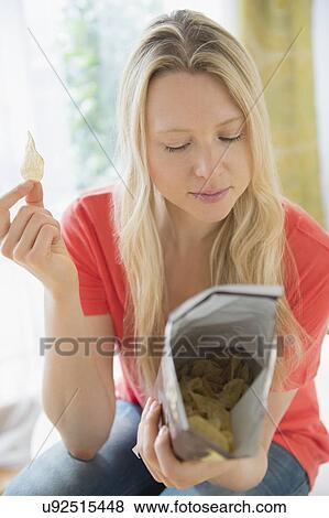 Woman eating crisps View Large Photo Image Stock Photo - Woman eating crisps. Fotosearch