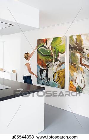 Woman hanging paintings indoors View Large Photo Image Stock Photo - Woman hanging paintings indoors. Fotosearch