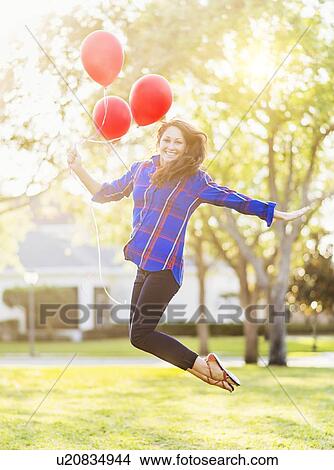 Woman holding balloons jumping View Large Photo Image Picture - Woman holding balloons jumping. Fotosearch