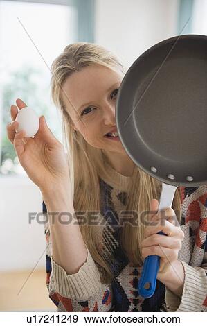 Stock Photo - Woman holding frying pan and egg. Fotosearch