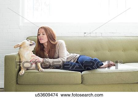 Woman lying on sofa stroking pug View Large Photo Image Picture - Woman lying on sofa stroking pug. Fotosearch