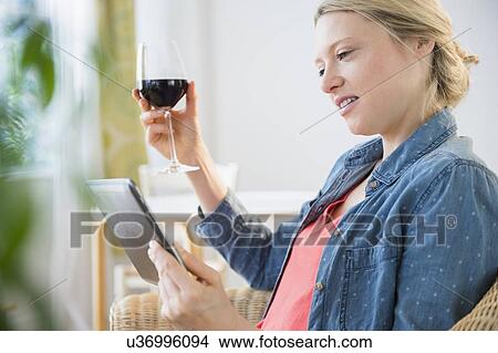 Woman sitting with digital tablet and glass of red wine View Large Photo Image Picture - Woman sitting with digital tablet and glass of red wine. Fotosearch