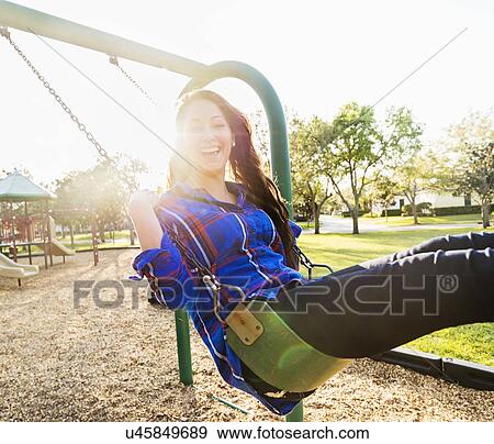 Woman swinging in playground View Large Photo Image Stock Photo - Woman swinging in playground. Fotosearch