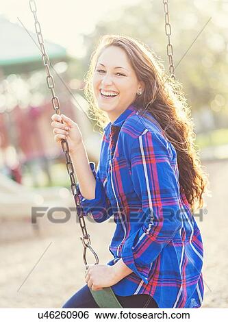 Stock Photograph - Woman swinging in playground. Fotosearch